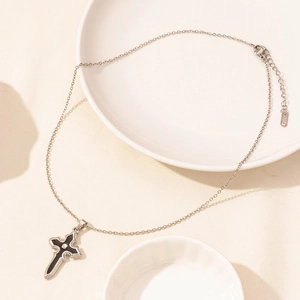 Detail of silver Gothic cross necklace with black enamel drip on white ceramic tray