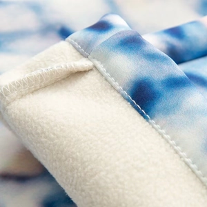 Detail of blue tie-dye outer fabric with warm white fleece lining and precision stitching