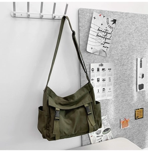 Vue détaillée du sac bandoulière en toile vert olive avec boucles et poches latérales