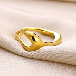 Detail of a golden irregular textured ring resting on elegant beige silk fabric