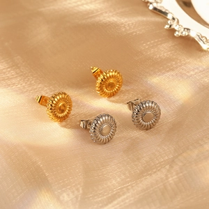 Elegant gold and silver sunflower-shaped stainless steel earrings on luxury gold fabric