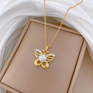 Macro view of gold butterfly pendant with pearl and small diamonds on silk