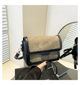 Detail of color-block flap bag with gold metal hardware held by a model in a cozy room