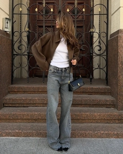 Brown zip-up jacket with white top and wide-leg jeans in a vintage street setting
