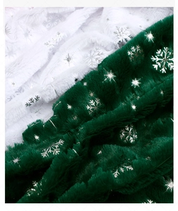 Macro view of green and white faux fur fabric with sparkling silver snowflake prints