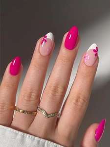 Detail of almond-shaped French press-on nails with bright pink floral art and gold rings