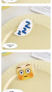 Detail showing acrylic cartoon hair clips with sleeping bubble and emoji on a tray