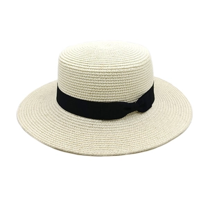 Close-up of cream boater straw hat with black grosgrain ribbon and bow detail