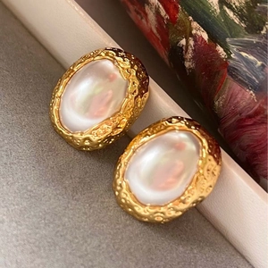Detail von Vintage-Goldohrringen mit unregelmäßigen Perlen und gehämmerter Optik