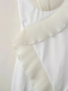 Détails des volants plissés blancs et de la dentelle délicate sur cette robe élégante