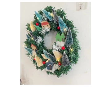 Detail of a glowing Christmas wreath with mini trees, red berries, and small houses
