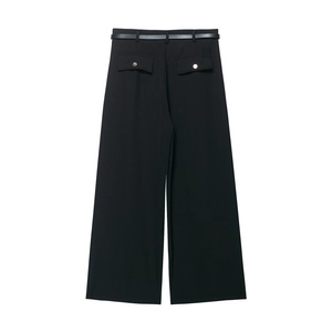Dettaglio dei pantaloni neri a gamba larga con cintura abbinata e tasche posteriori dorate