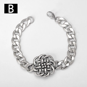 Macro detail of silver stainless steel Cuban chain bracelet with vintage Celtic knot charm