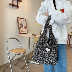 Detail of grey leopard print faux shearling tote bag in a cozy cafe setting