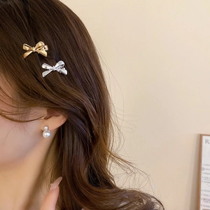 Close-up of minimalist gold and silver bow hair clips and elegant pearl earrings on a model