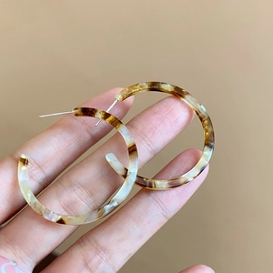 Detail view of retro resin C-shaped hoop earrings with amber marble pattern and silver pins