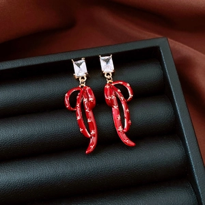 Detailed macro of red enamel bow earrings with zircon and gold-plated finish