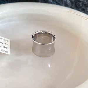 Close-up of a wide polished silver ring with a sleek concave surface and mirror finish