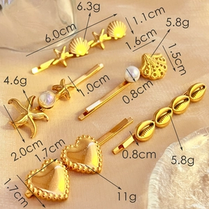 Five golden stainless steel hair clips with shell and pearl motifs on beige silk