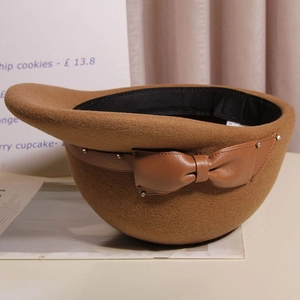 Close-up of wool felt equestrian hat with leather bow and rivet detail in camel brown