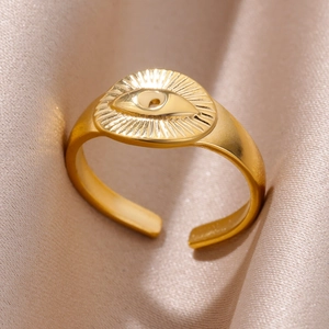 Macro shot of gold-plated evil eye ring detail with radial sunburst texture on silk