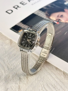 Detail of silver square steel band watch with black dial on a magazine background