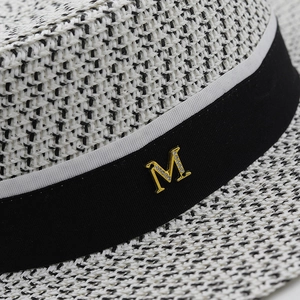 Macro detail of straw hat weave with black grosgrain ribbon and crystal M metal buckle