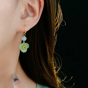 Detailed close-up of a green flower drop earring with a gold hook and zircon accents