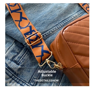 Detail of V-quilted brown leather bag featuring an orange woven strap with metal buckle