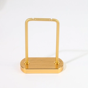 Minimalist gold metal earring display stand with a sturdy rectangular base on white background