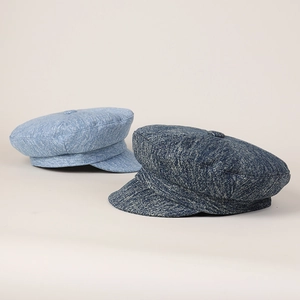 Close-up of navy and light blue denim baker boy hats with textured fabric and top button