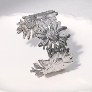 Polished stainless steel wide cuff bangle featuring detailed daisy sunflower pattern