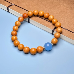 Detailed close-up of sandalwood bead bracelet with a blue accent bead and metal spacers