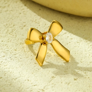 Macro view of gold bow-shaped ring with center oval clear zircon on stone background