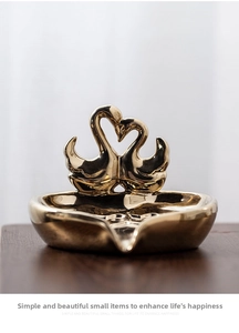 Detail of elegant gold twin swan ceramic jewelry tray with a polished mirror finish