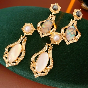 Gros plan sur des boucles d'oreilles ovales vintage avec incrustation de nacre