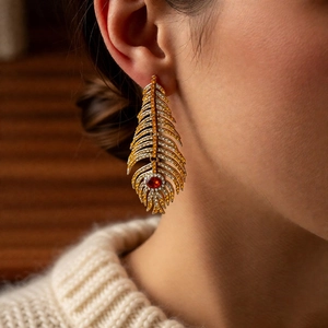 Close-up of vintage feather drop earring with amber rhinestones on model's ear