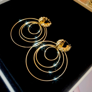 Dettaglio di orecchini multistrato dorati con strass in una confezione regalo nera