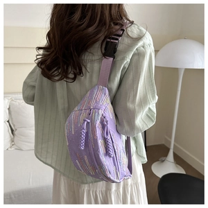 Detail of purple quilted crossbody bag with adjustable strap worn by model in home setting