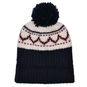 Gros plan d'un bonnet en maille épaisse avec motif cœur géométrique et pompon bleu marine