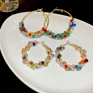 Bohemian gold hoop earrings with colorful crystal beads and white pearls set on white plate