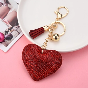 Macro view of red rhinestone heart keychain with burgundy tassel on a decorative tray