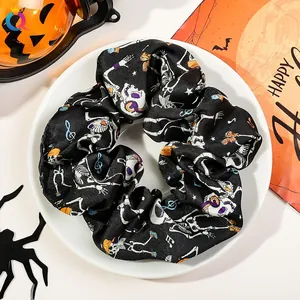 Halloween theme satin hair scrunchie with skull print on a white plate with pumpkins