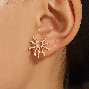 Vue rapprochée de boucles d'oreilles soleil dorées avec design rayon sur le mannequin