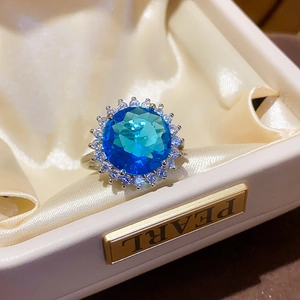 Close-up of sparkling blue zircon ring with halo setting in a luxury jewelry box