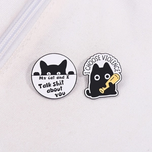 Cartoon black cat enamel pins featuring witty quotes on a beige canvas surface
