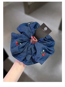 Close-up of denim blue scrunchie featuring red cherry embroidery and small pearls