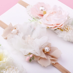 Detailed macro view of chiffon and lace floral baby headbands with delicate pearl accents