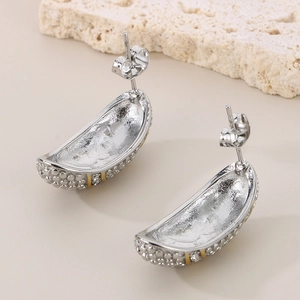 Macro detail of crescent stainless steel earrings with textured relief and gold trim