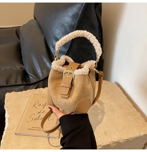 Detail of suede bucket bag with faux fur trim on a stone surface for winter